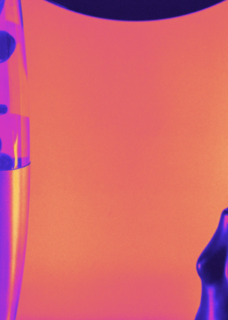 A modern lava lamp and a small glossy figurine sit on a surface beneath a large vinyl record, all lit with dramatic pink, purple, and orange neon lighting.